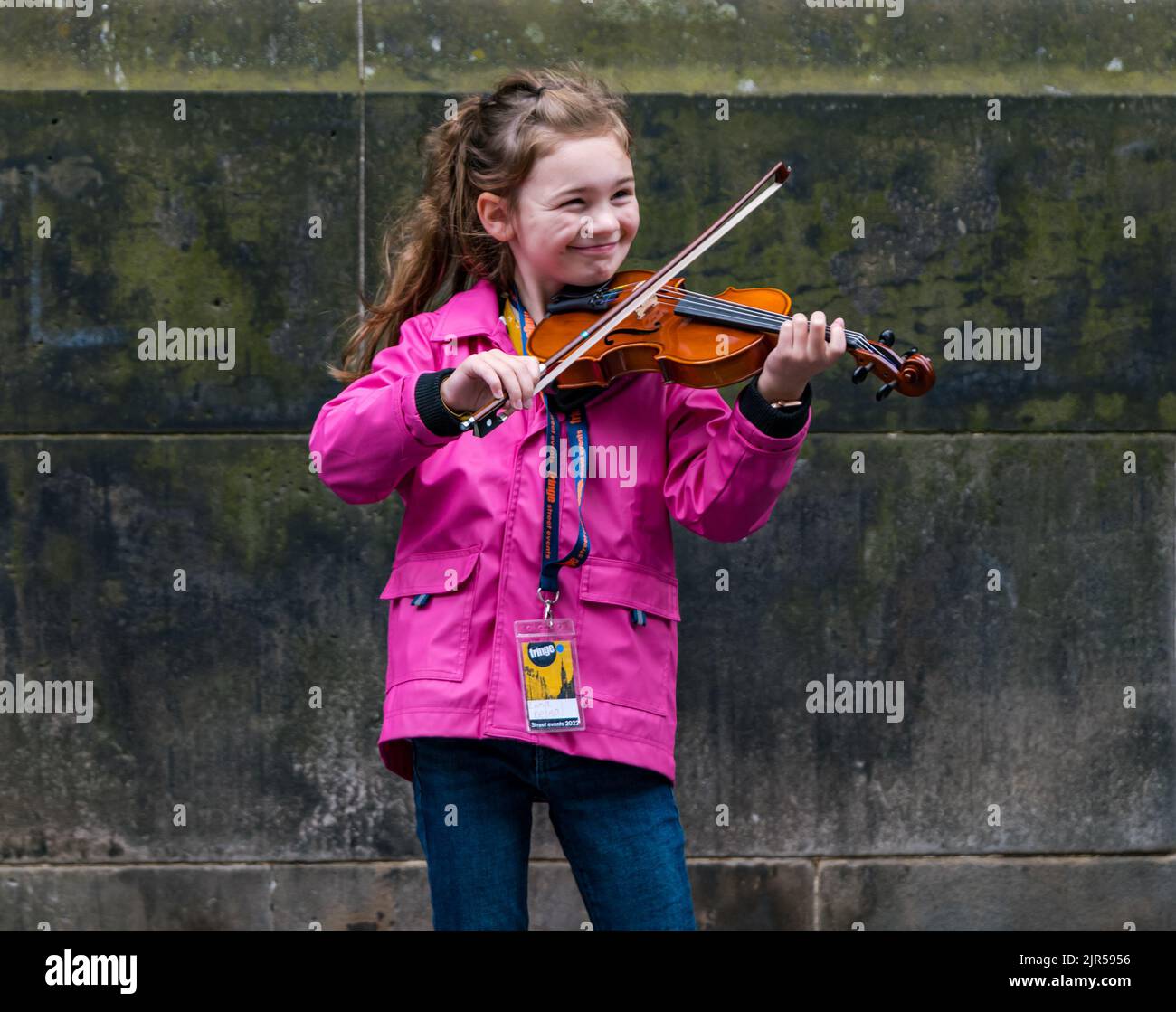 Royal Mile, Edinburgh, Scotland, UK, 22nd August 2022. Fringe performers: a very young street busker called Emma Deimal performs outside St Giles Cathedral playing fiddle music.  Credit: Sally Anderson/Alamy Live News Stock Photo