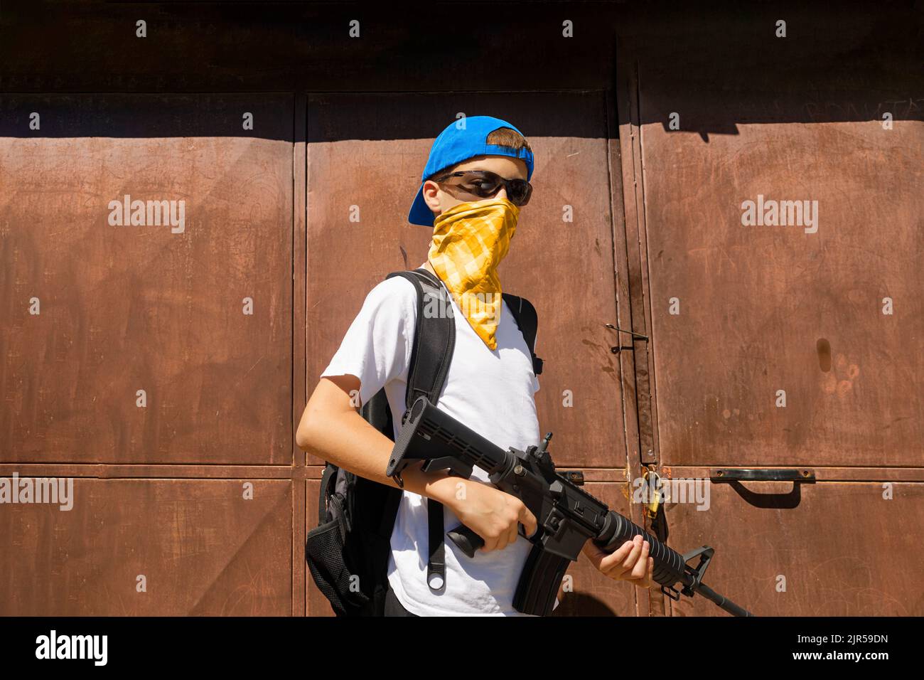 Armed underage male with a bandana and sunglasses Stock Photo