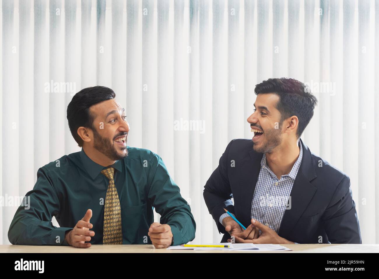 Corporate co-workers talking and laughing while sitting together. Stock Photo