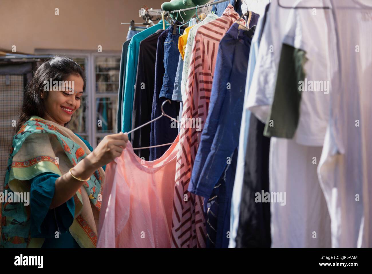 Young woman hanging clothes on washing line to dry outside Stock Photo