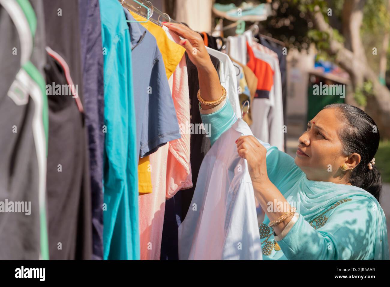 Senior woman hanging clothes on washing line to dry outside Stock Photo