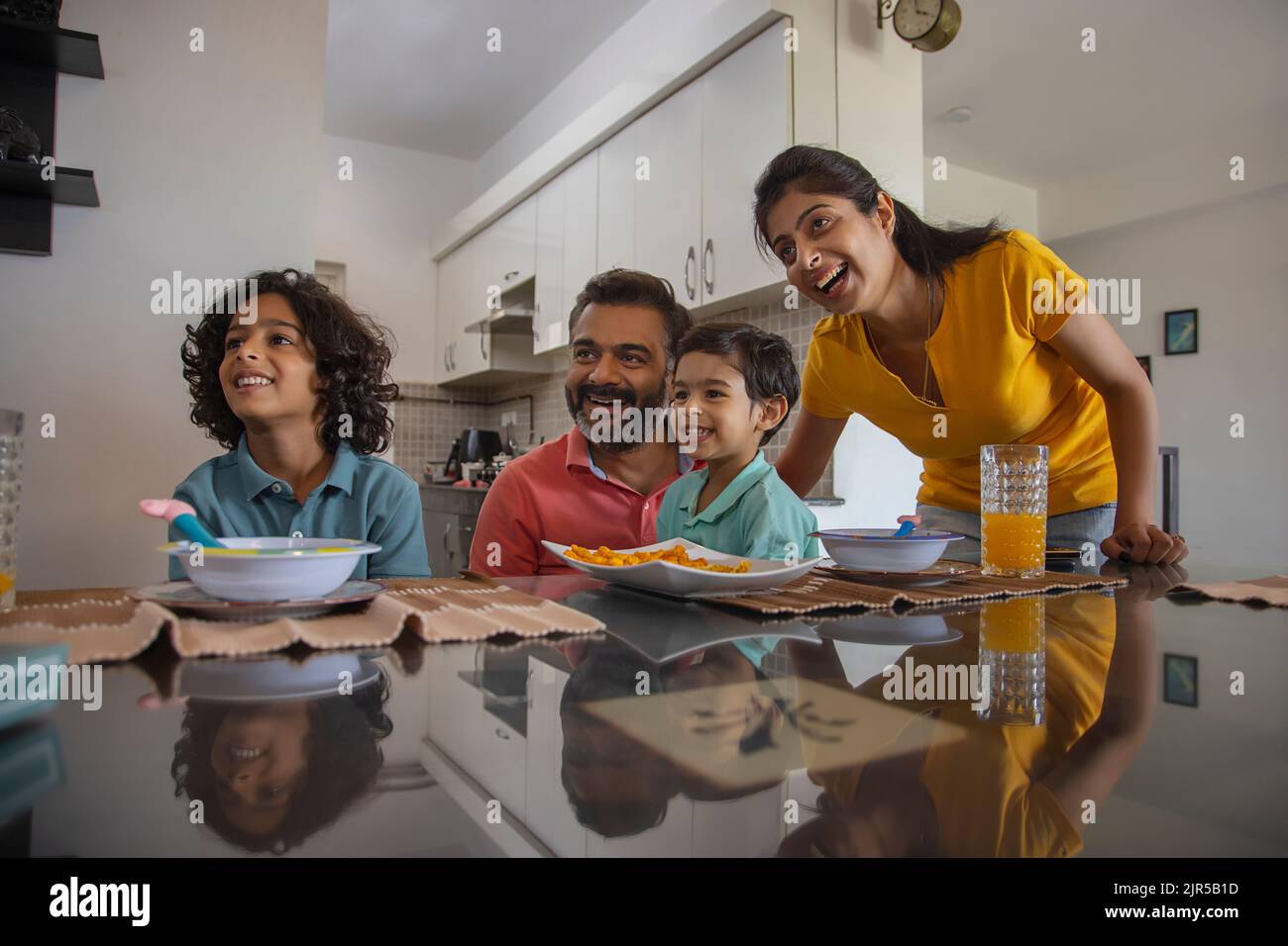 Portrait of a happy nuclear family looking away during breakfast Stock Photo
