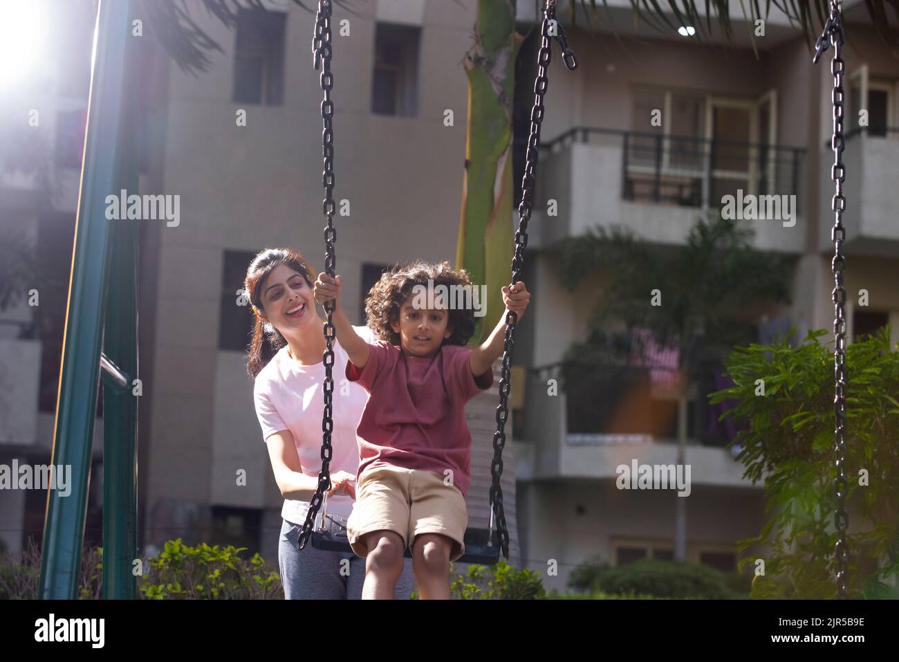 Mother pushing her son on swing in the park Stock Photo - Alamy