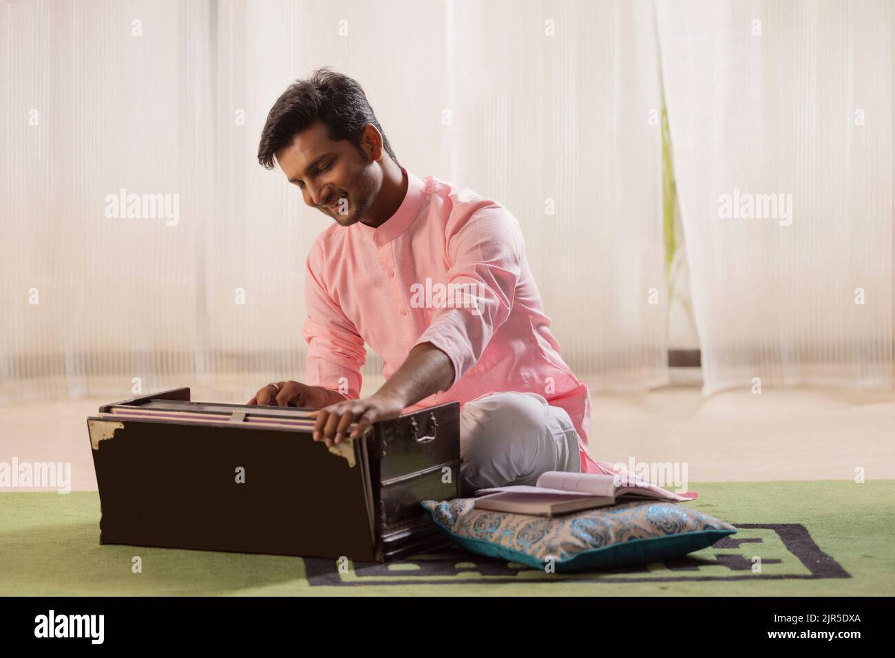 Portrait of young man playing harmonium at home Stock Photo