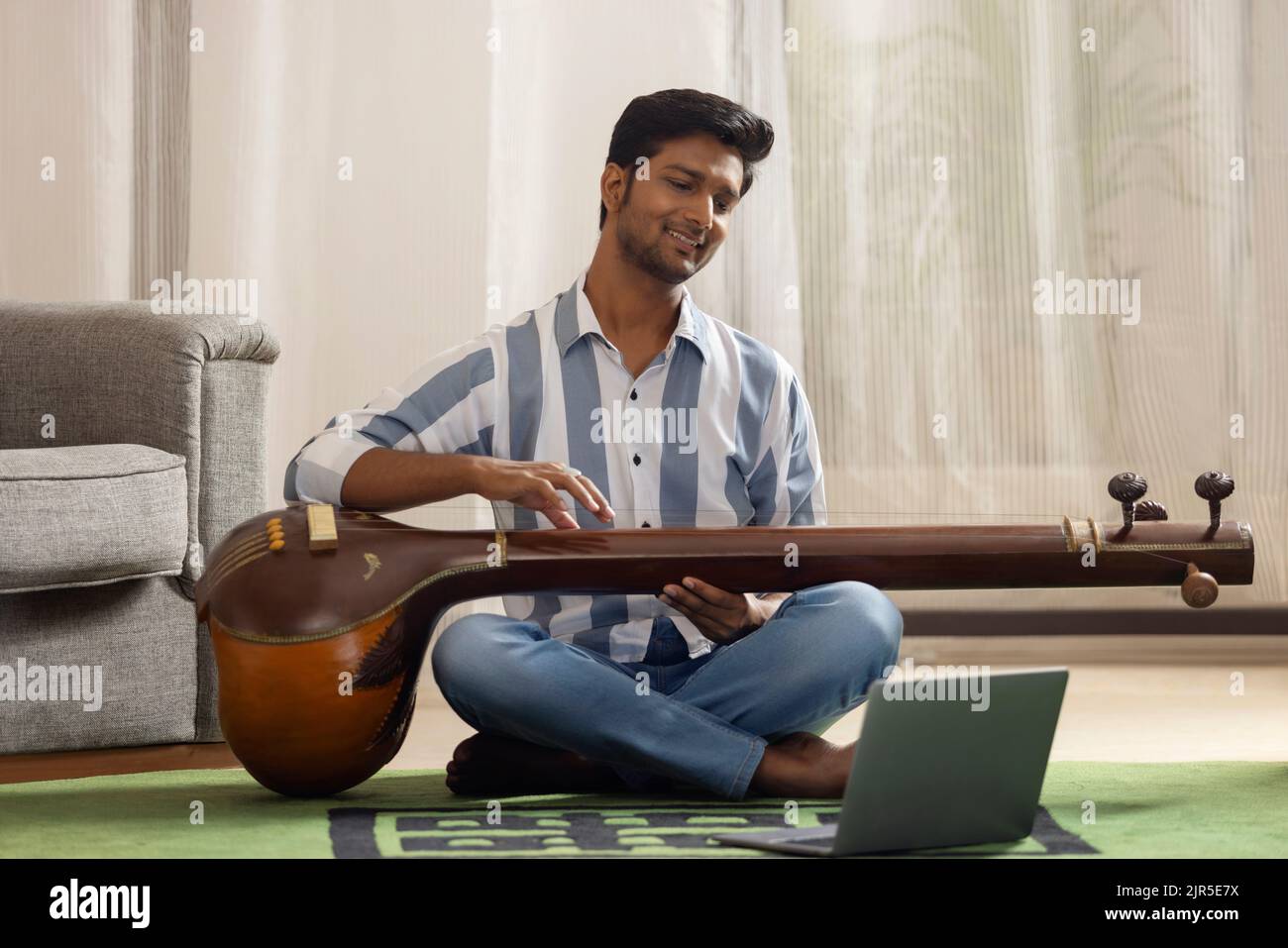 Portrait of young man having online Tanpura lesson Stock Photo