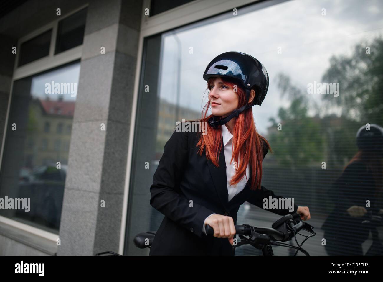 Portrait of businesswoman commuter on the way to work with bike, sustainable lifestyle concept. Stock Photo