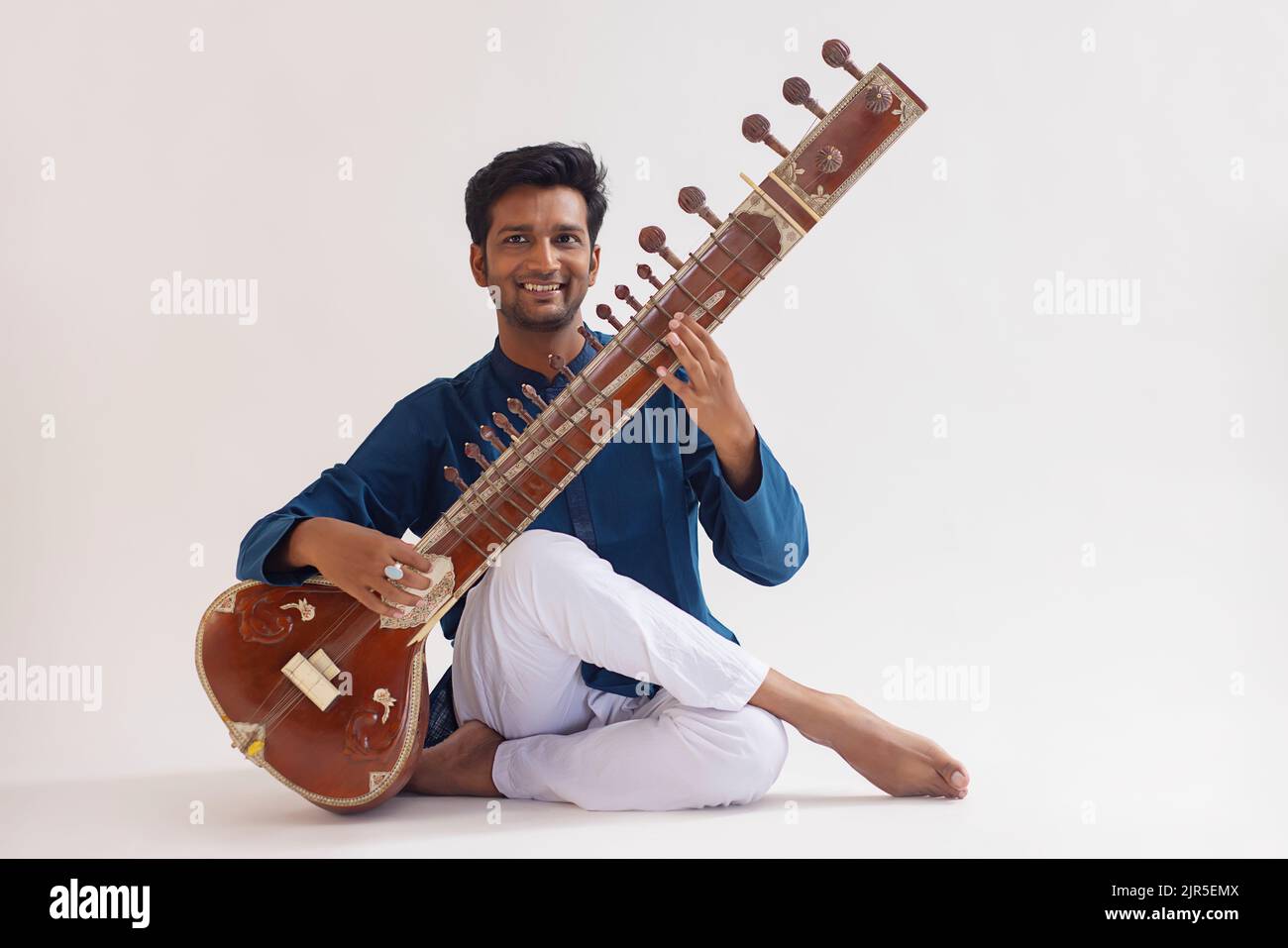 Portrait of cheerful young man playing sitar Stock Photo