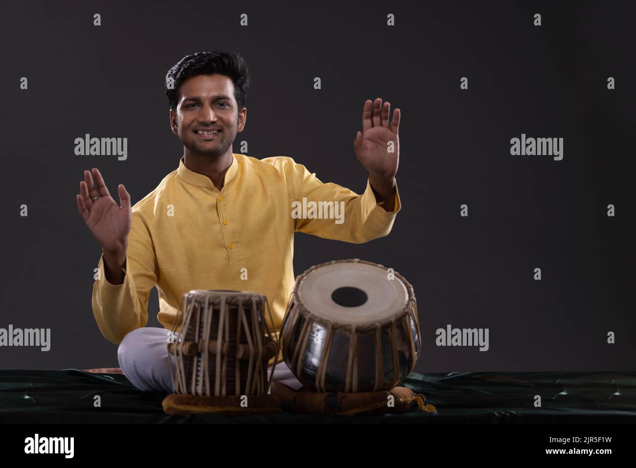 Portrait of cheering young man performing with Tabla on stage Stock Photo