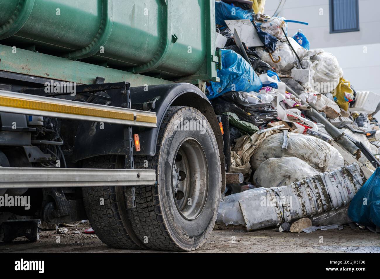 Modern Garbage Truck Close Up and the Pile of Trash. Waste Management Theme. Stock Photo