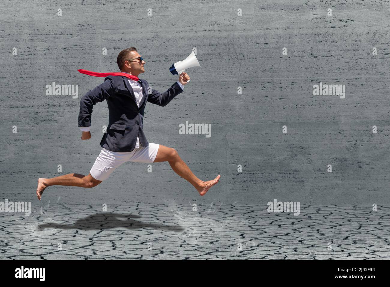 Businessman runs with megaphone on gray background. Advertising concept. Stock Photo