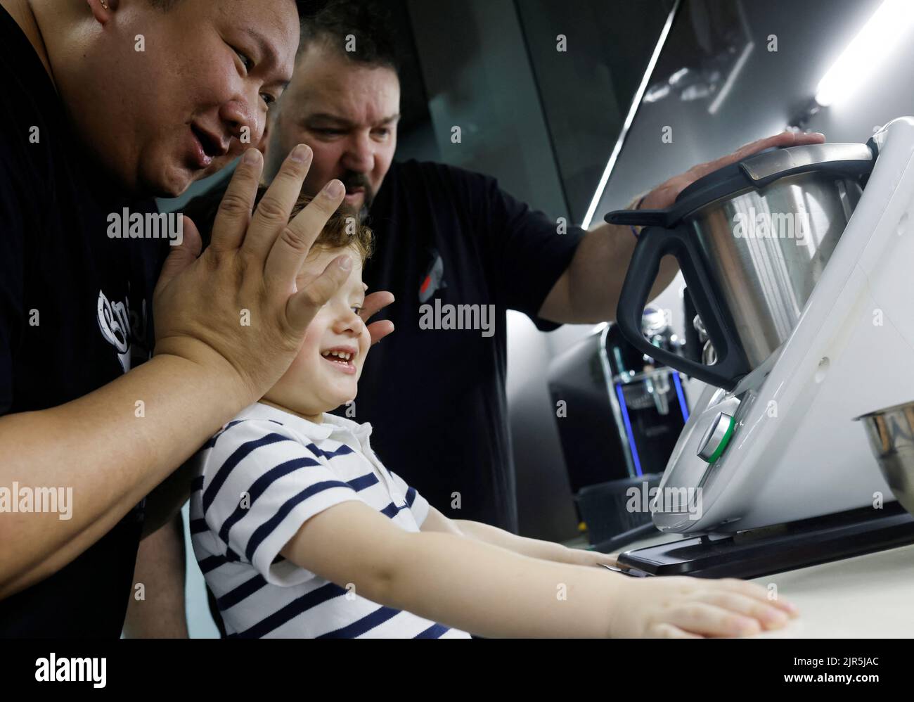 Same-sex parents Andre Ling, 44, and Cameron Sutherland, 47, cover their two year old son Tyler's ears as they crush rock sugar to make lemonade in a Thermomix machine at home in Singapore, August 22, 2022. REUTERS/Edgar Su Stock Photo