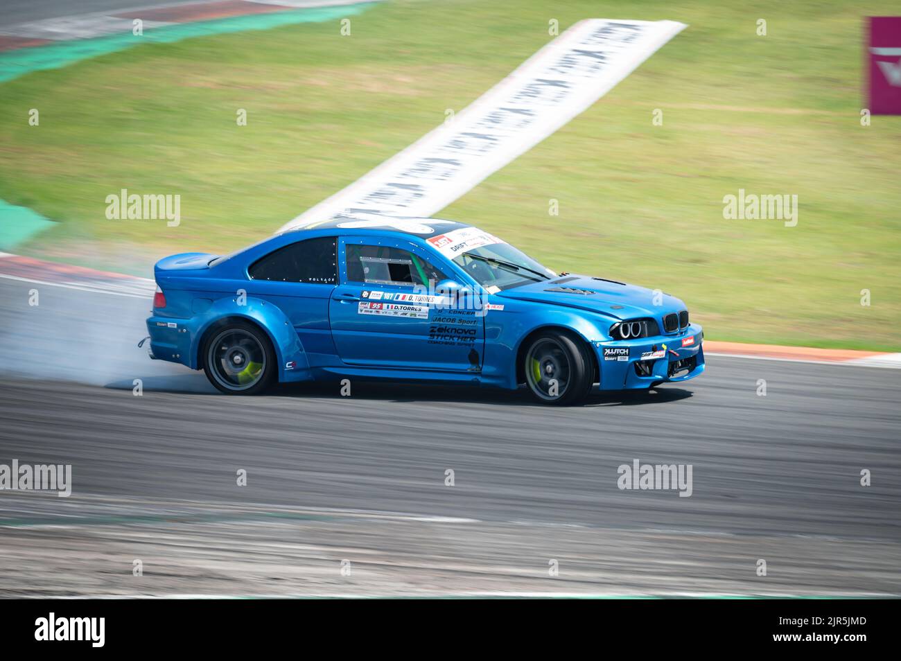 A blue BMW E46 producing smoke on a trail for a drift competition Stock Photo