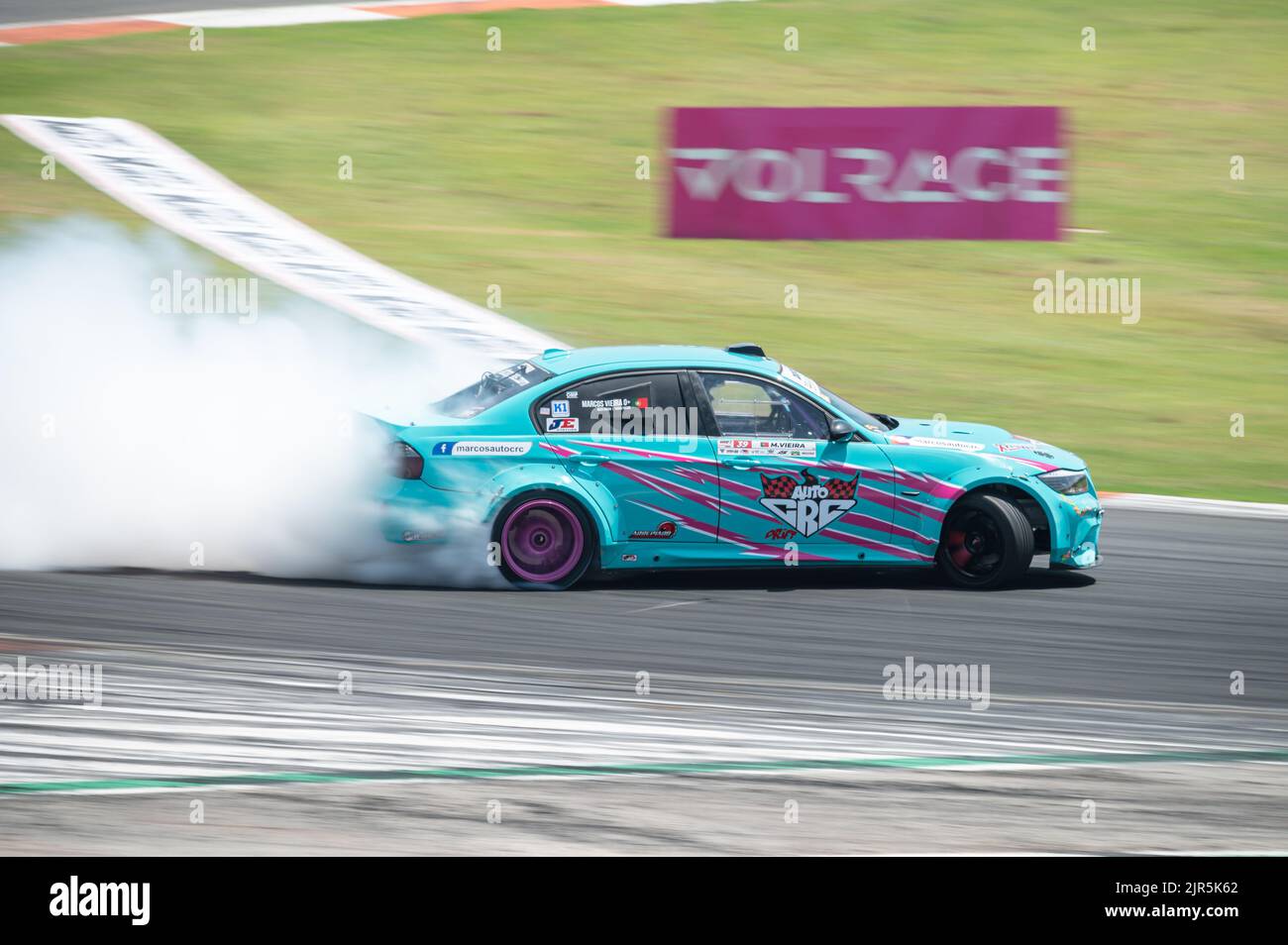A blue BMW E90 Series 3 producing smoke on a trail for a drift competition Stock Photo