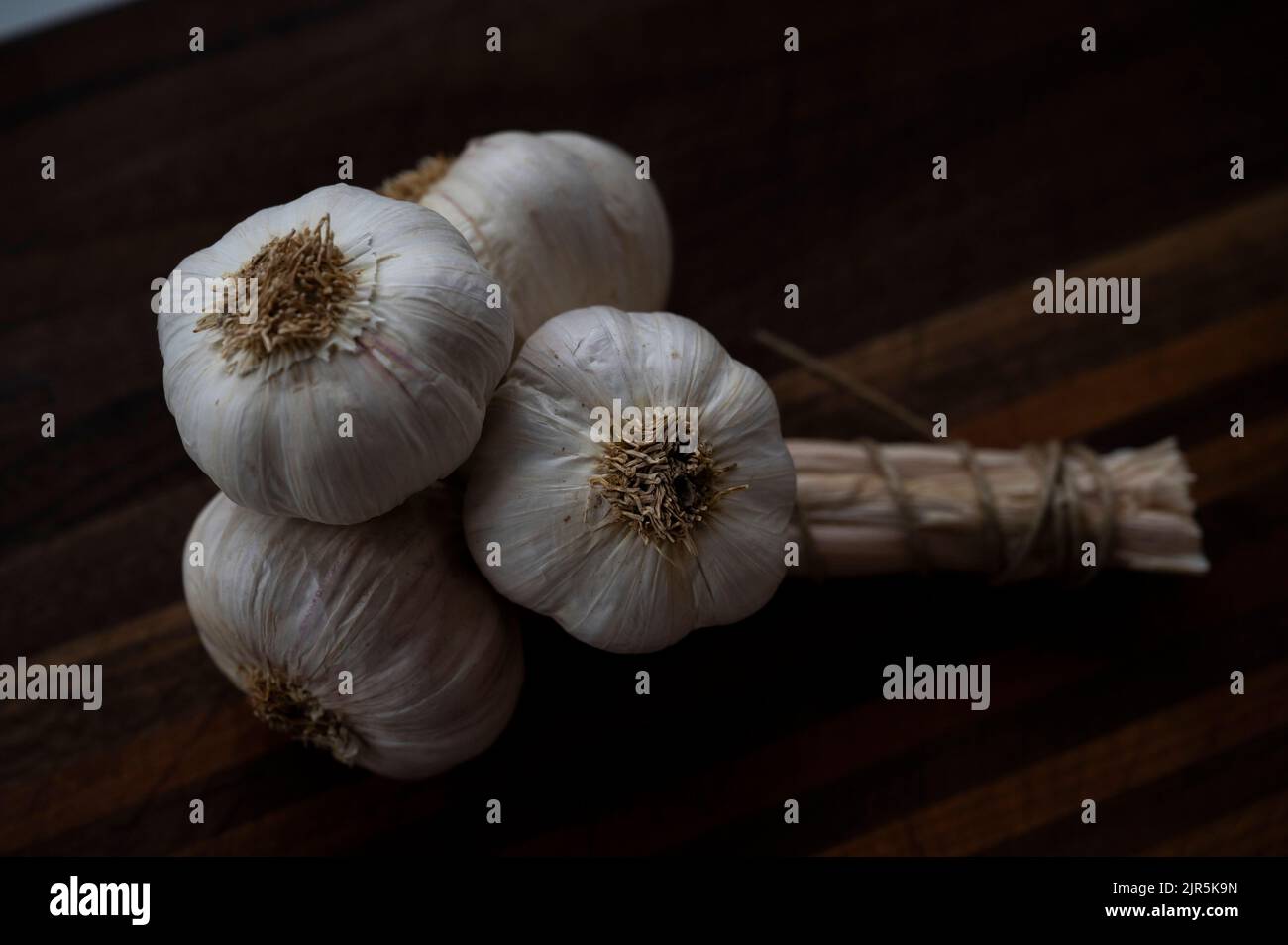 A bunch of garlic cloves on a chopping board Stock Photo
