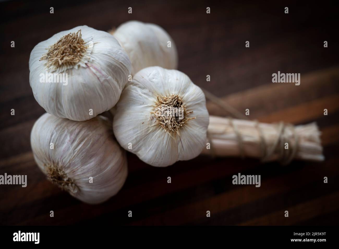 A bunch of garlic cloves on a chopping board Stock Photo