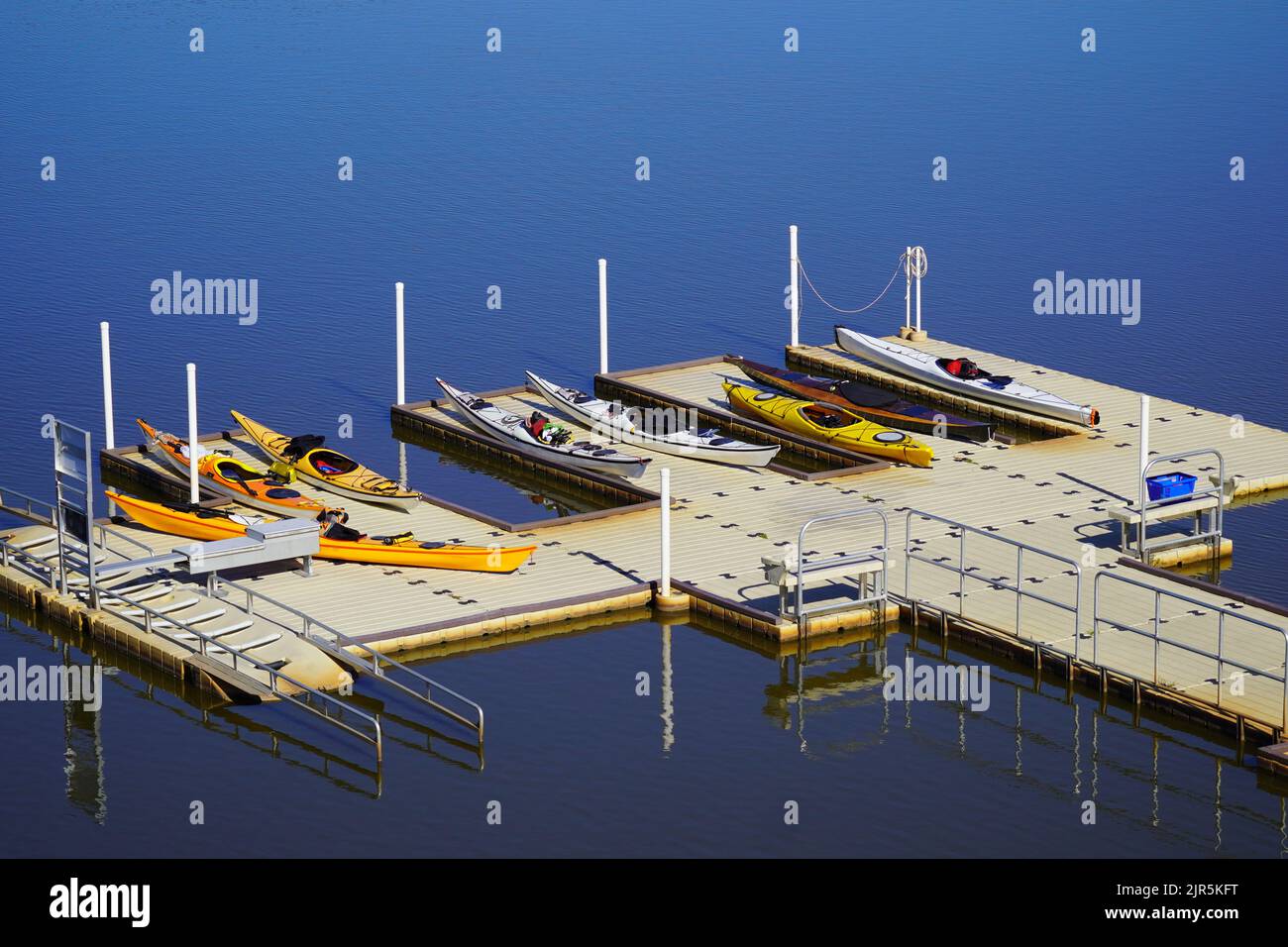 Set of colorful kayaks sitting on a dock by a lake Stock Photo