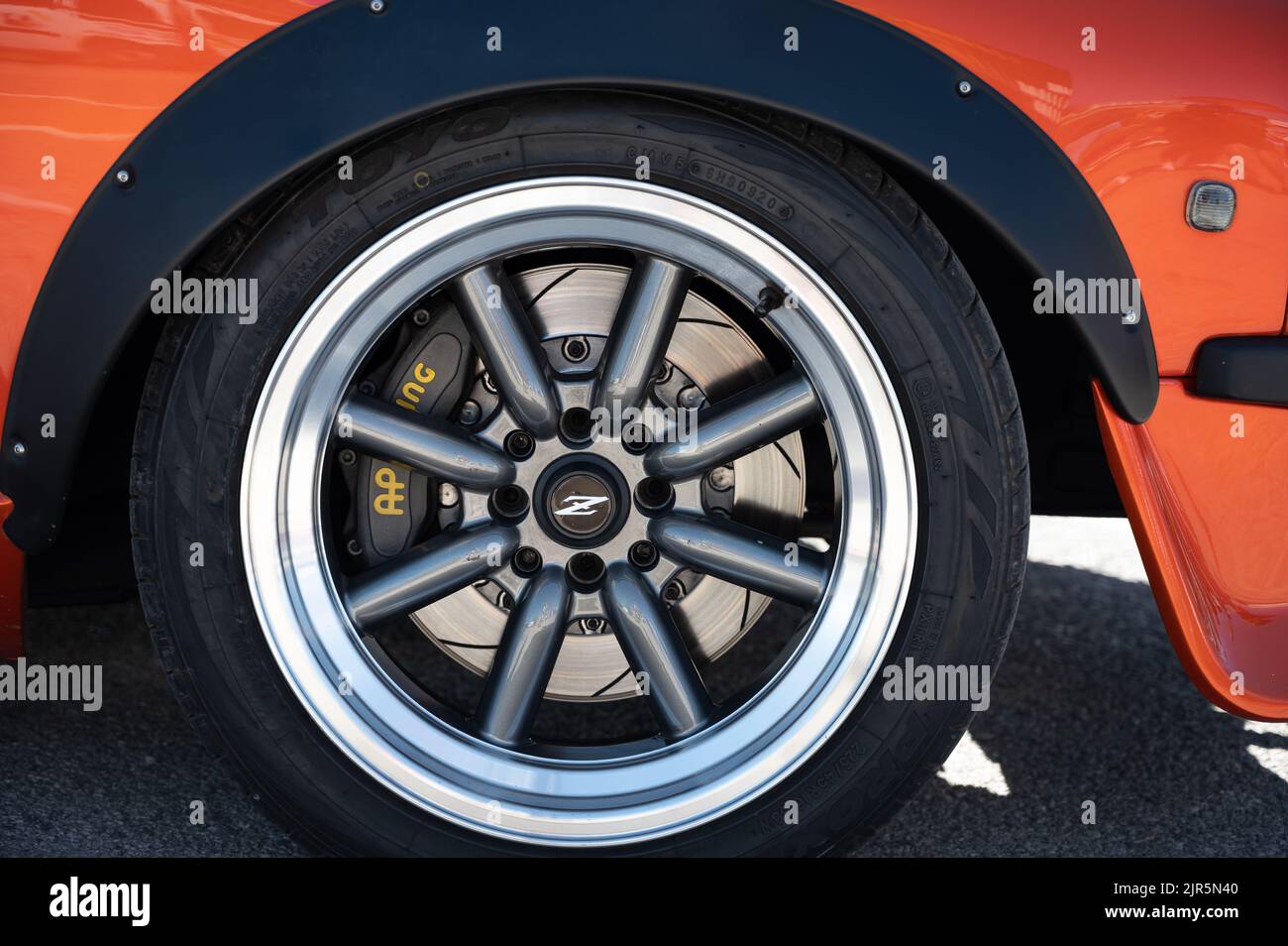 The details on the wheels of a classic orange Japanese Datsun 240z parked at an exhibition Stock Photo