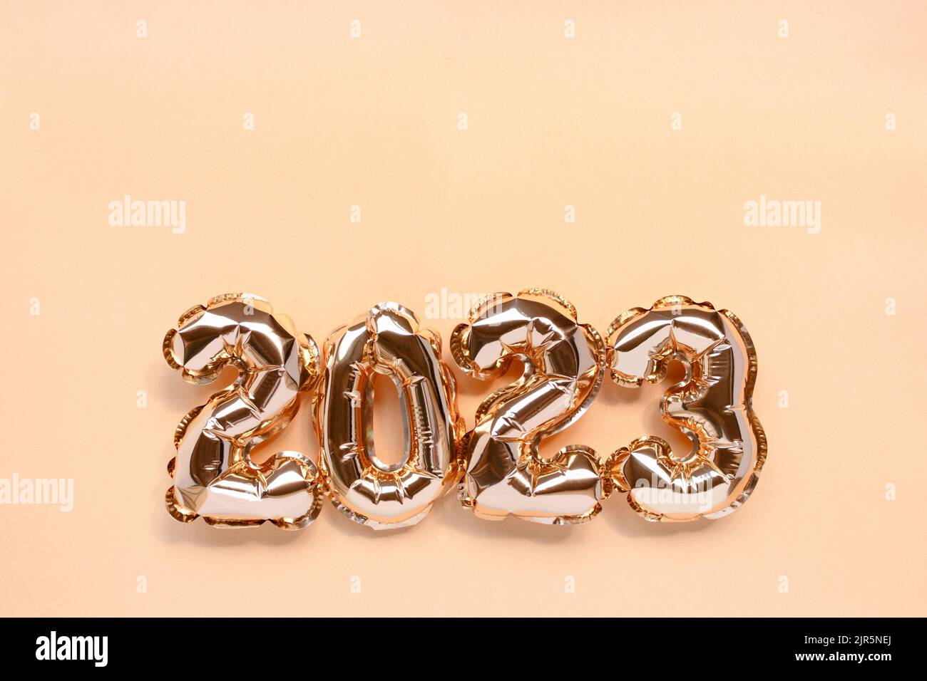 2023 golden balloons on a shiny background with copy space. Monochrome New Year's composition. Stock Photo