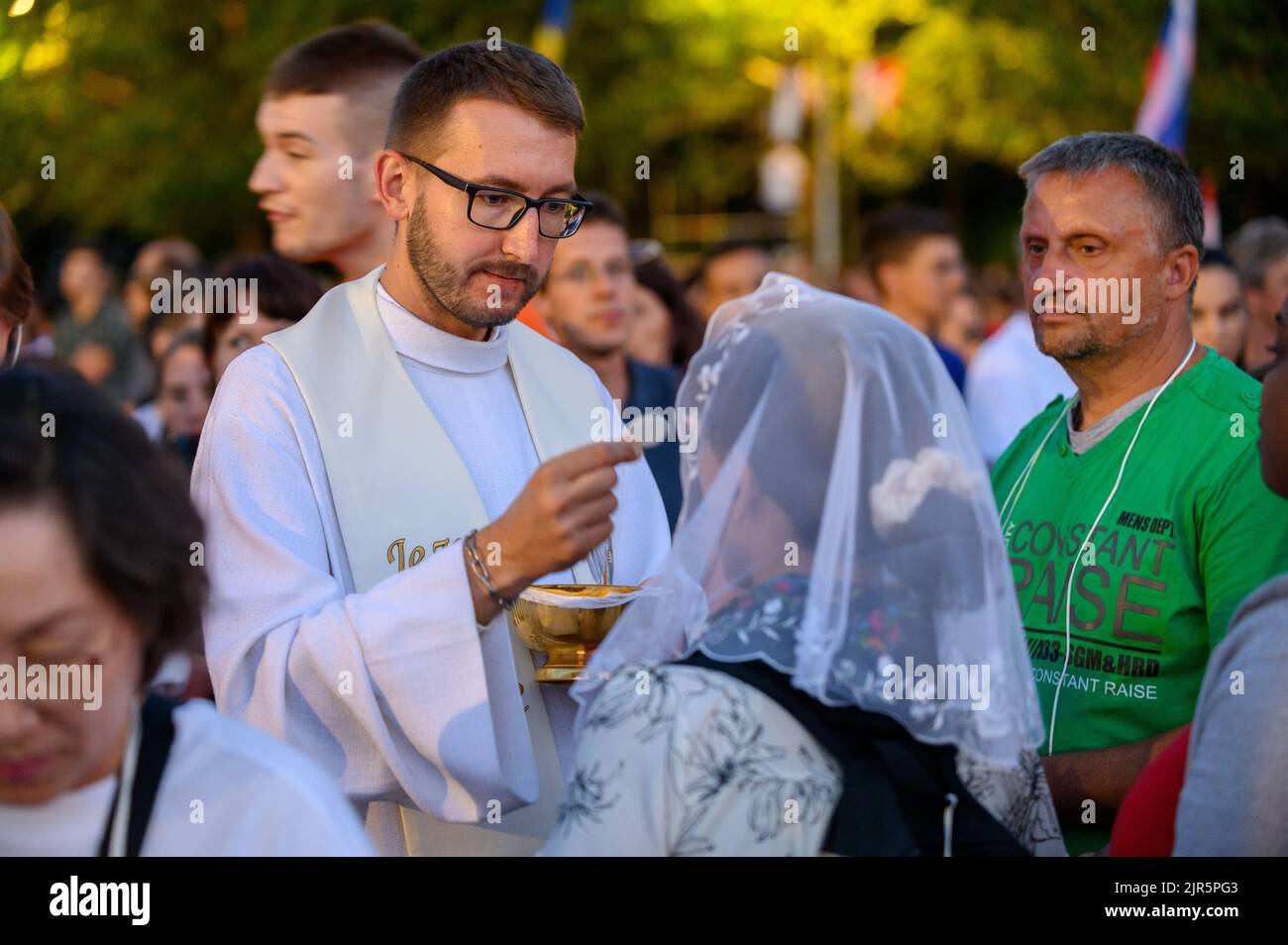 A priest giving the Holy Communion to the faithful. Stock Photo