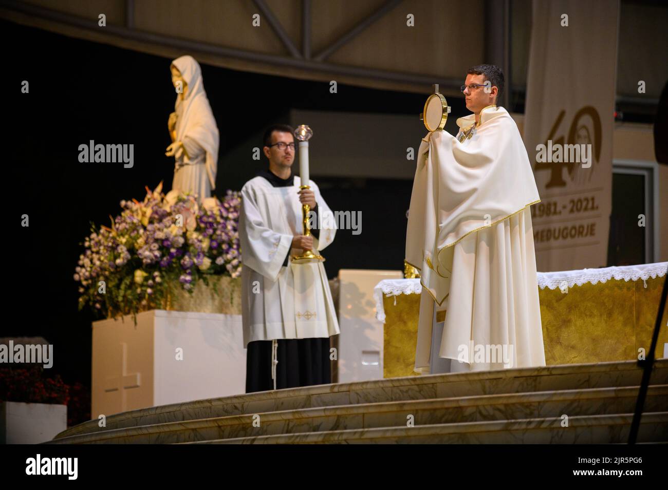 A priest blessing the faithful with the Blessed Sacrament at the conclusion of a Eucharistic adoration in Medjugorje, Bosnia and Herzegovina. Stock Photo