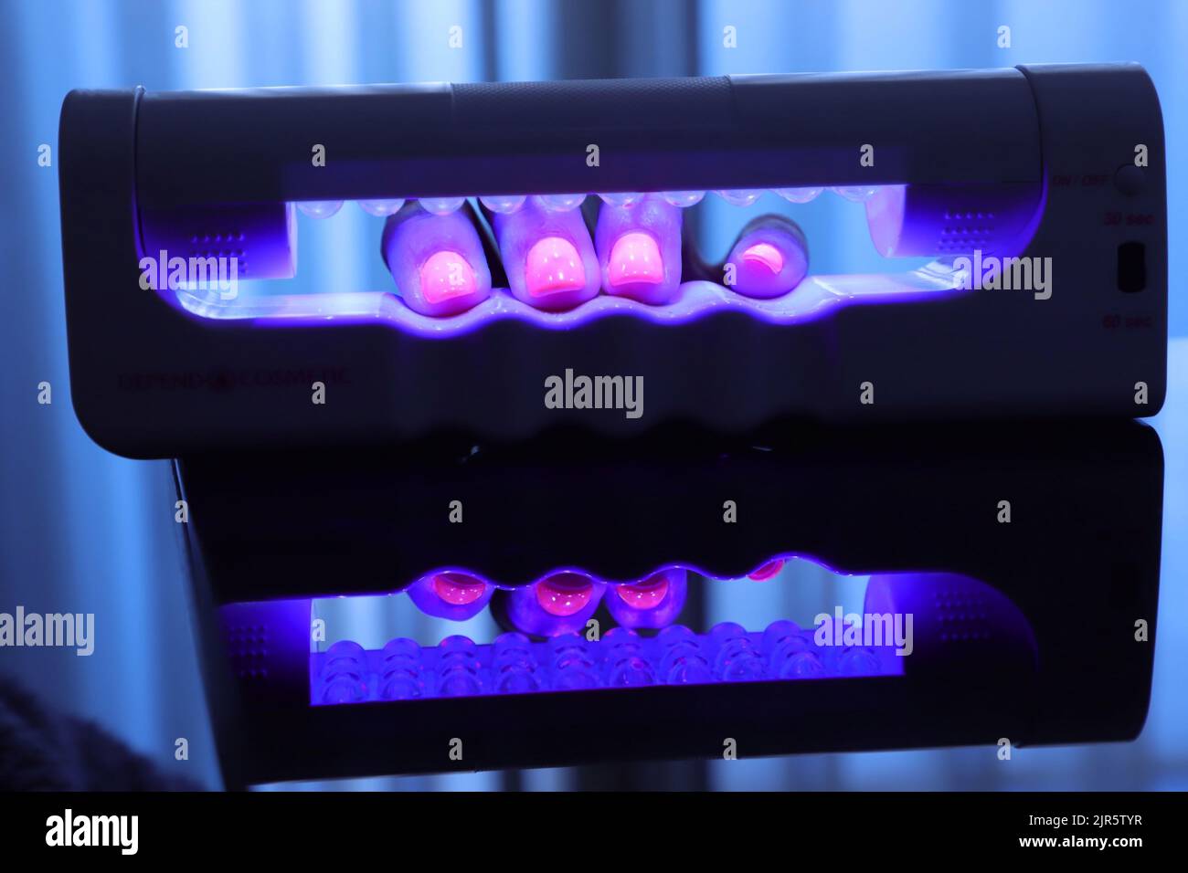 the-close-up-view-of-polished-nails-under-the-ultra-violet-lamp-stock