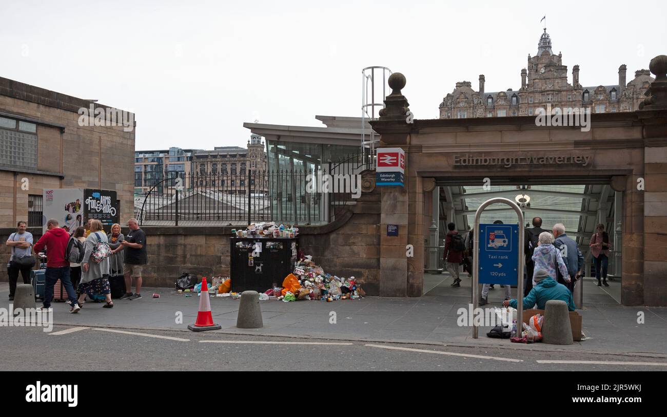 Waverley Station, Edinburgh, Scotland, UK. 22nd August 2022. Bad enough to arriive on holiday and be greeted by dull and drizzly weather although temperture is 17 degrees centigrade, but even worse is refuse bins on the pavements piled high and overflowing with discarded rubbish immediately outside the train station entrance. This is due to cleansing workers from the City of Edinburgh Council being on their fifth day of an eleven days of strike action over pay.  Credit: Arch White/alamy live news. Stock Photo