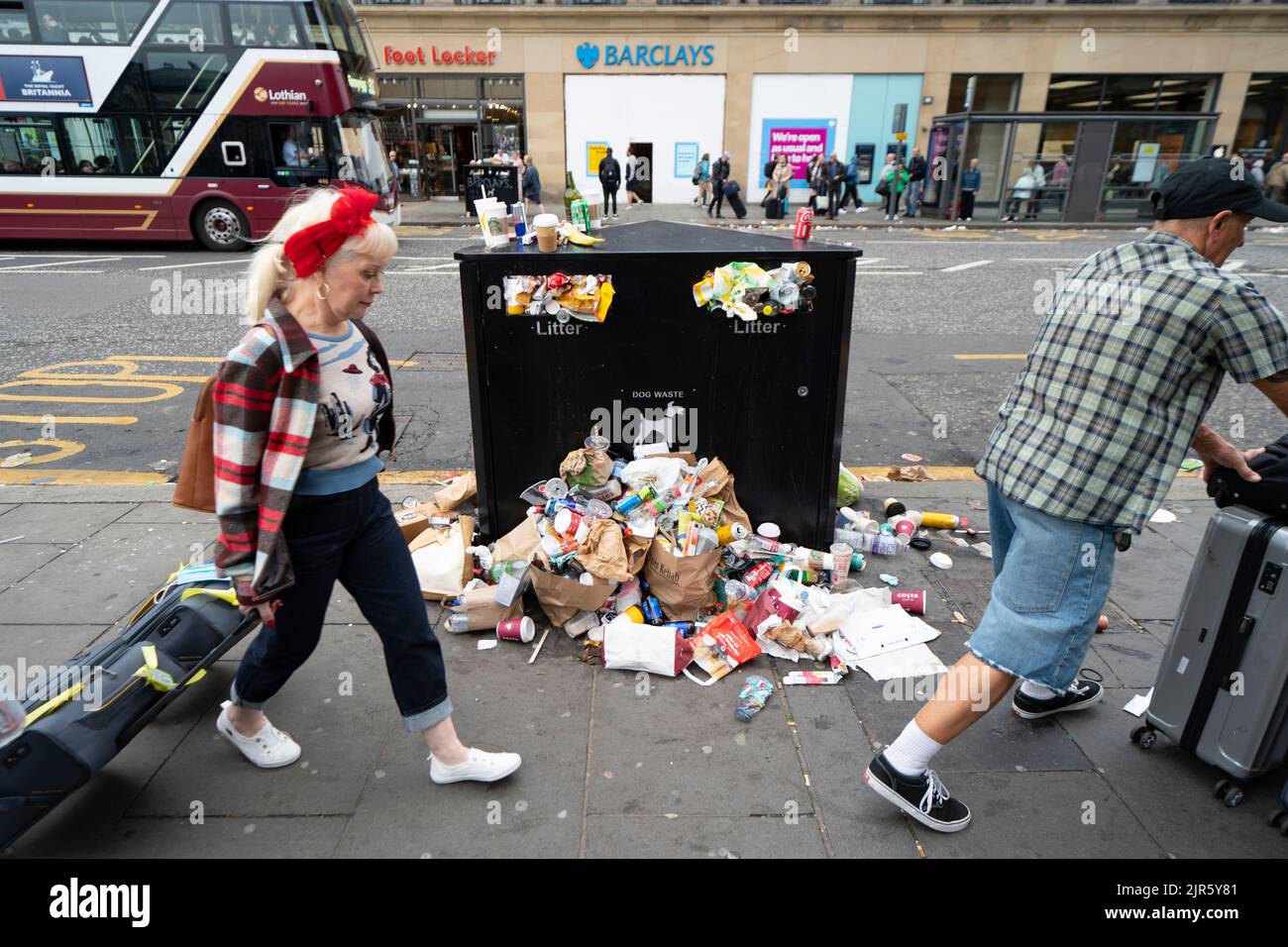 Edinburgh, Scotland, UK. 22nd August 2022. Refuse is seen piled on the streets of Edinburgh city centre on day five of a 12 day strike by city refuse collectors. The strike is organised by the United and GMB unions and is as  a result of the Unions rejecting a 3.5% pay increase. Pic；Tourists walk past overflowing bins on princes Street. Iain Masterton/Alamy Live News Stock Photo
