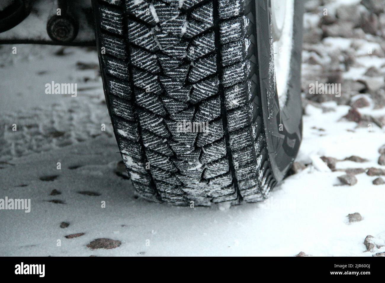 Snow on a winter tire tread blocks on a gravel road detailed Stock Photo