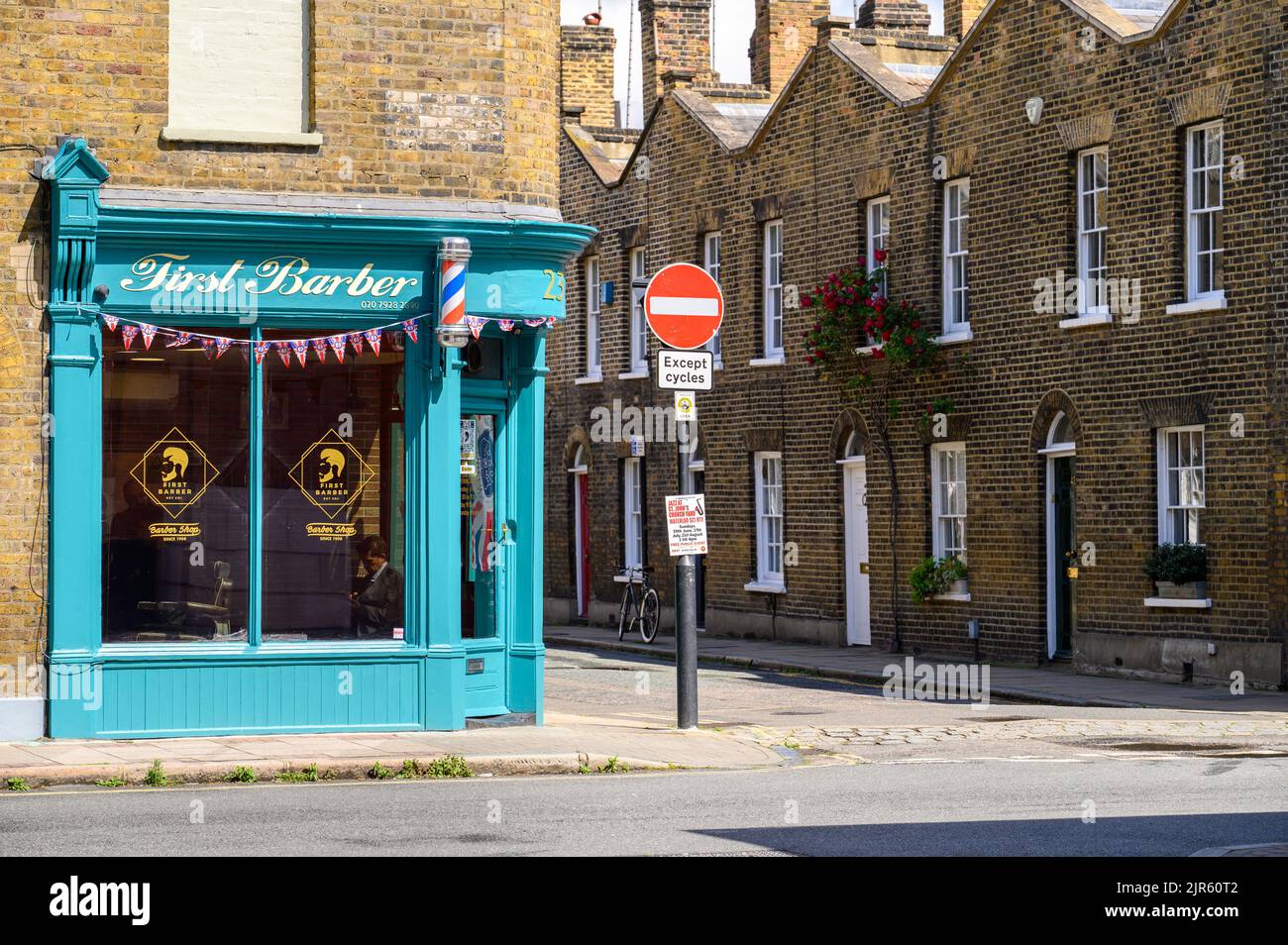 LONDON - May 20, 2022: Barber shop and No Entry road sign on corner of a street. Old brick terrace houses in background Stock Photo