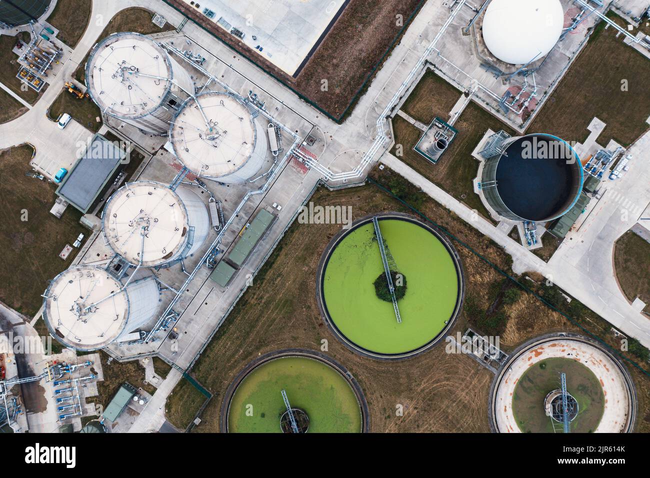An aerial view directly above a waste water treatment works with circular storage tanks filtering wastewater with green algae for drinking water Stock Photo