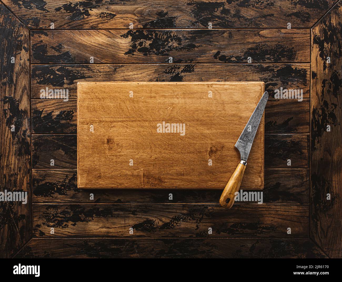 Vintage meat cleaver on empty old wooden cutting board. Top view, space