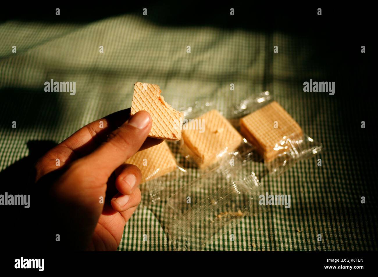 Hand holding square wafer biscuits in transparent plastic package Stock Photo