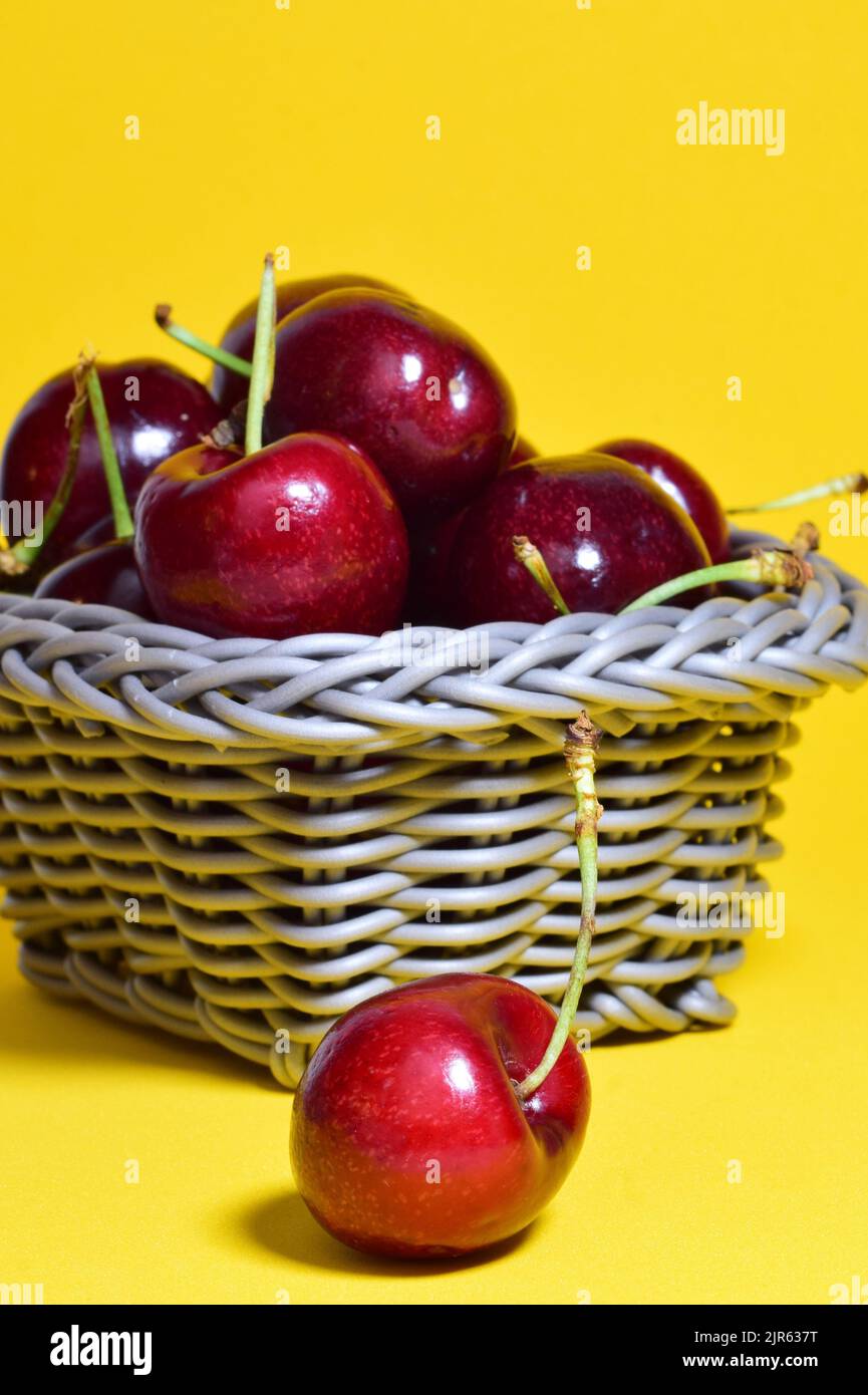 A ripe cherry season on basket and yellow background Stock Photo Alamy