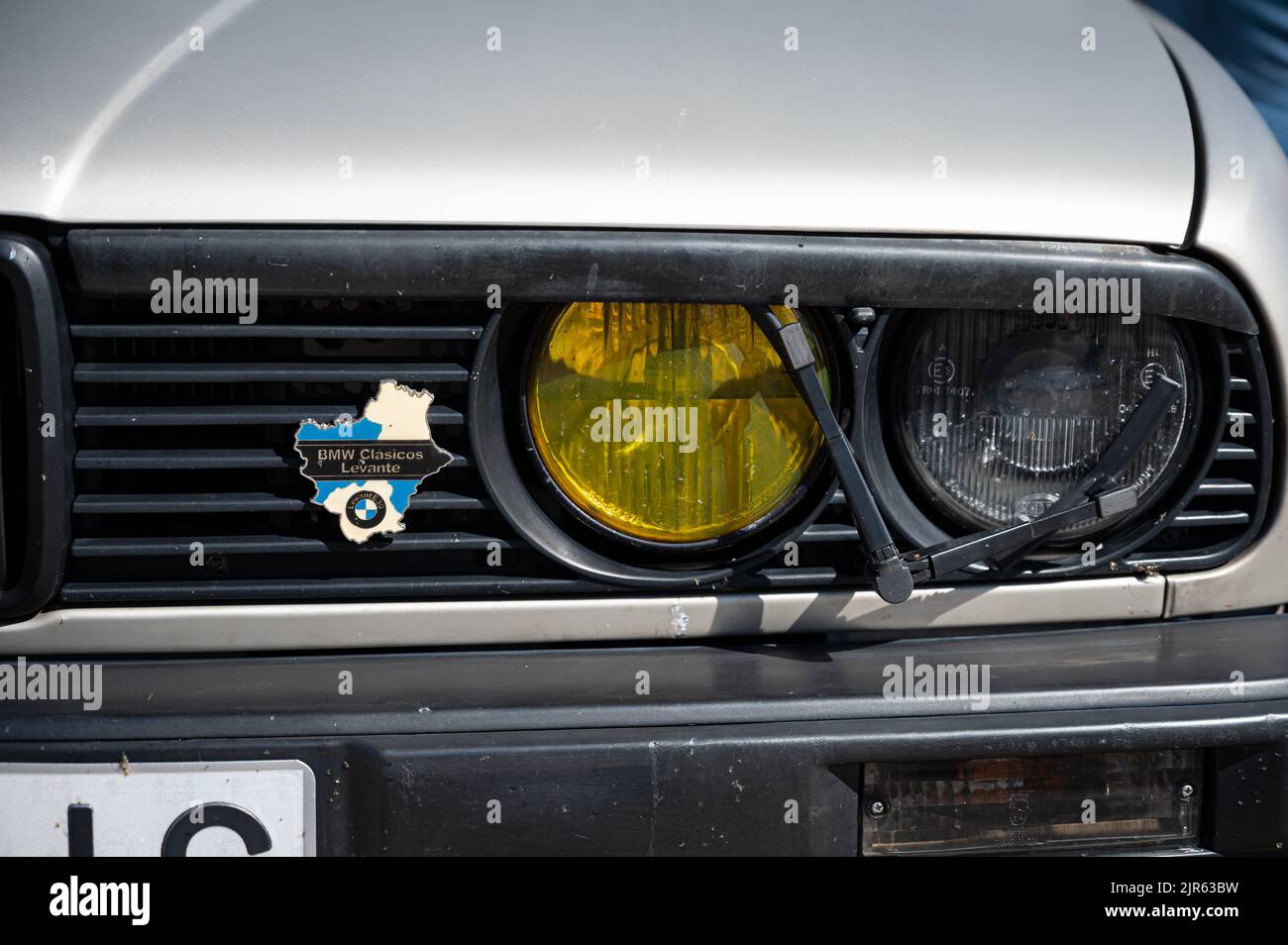 A closeup shot of the front of a classic BMW E30, headlight washer