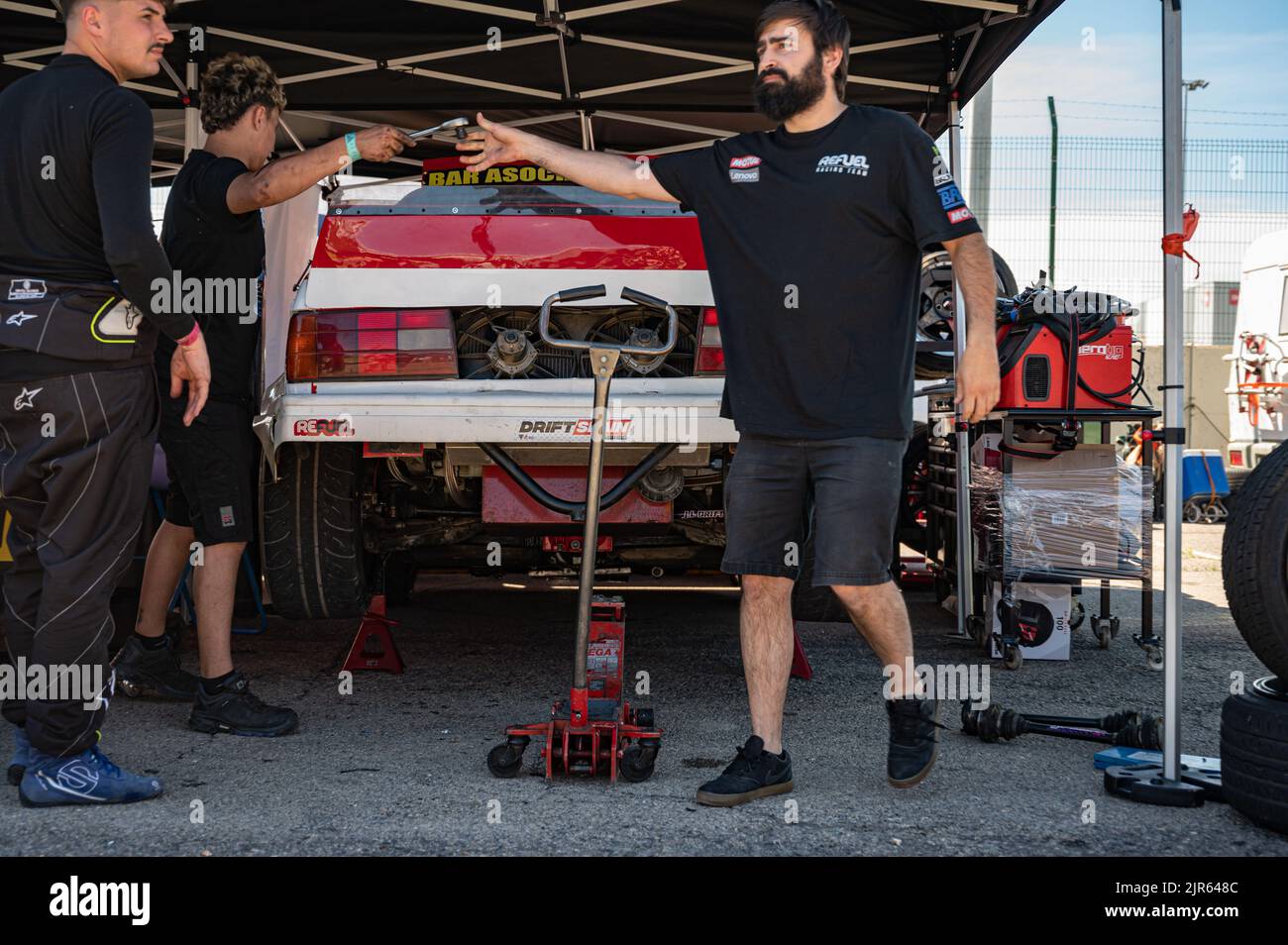 The BMW E30 in pits, mechanics have raised the car with the jack to change the bearings and axles Stock Photo