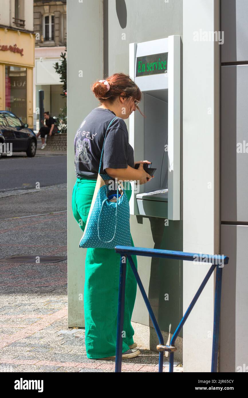 Woman at cash dispenser, Limoges, Haute-Vienne (87), France. Stock Photo