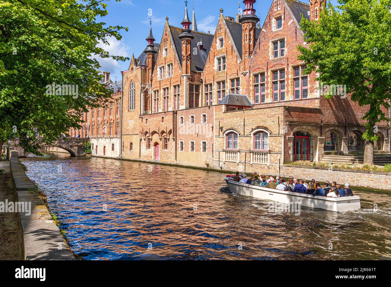 Tourists enjoying a guided boat tour around the canals of Bruges, Belgium Stock Photo