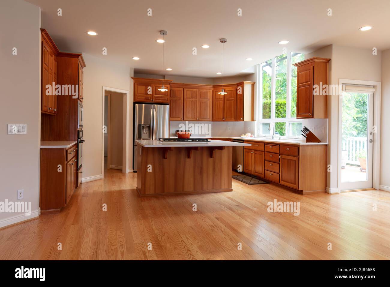 Remodeled kitchen in luxury home with island plus built in stove top, pendant lights, real red oak hardwood floors, cherry cabinets and stainless stee Stock Photo