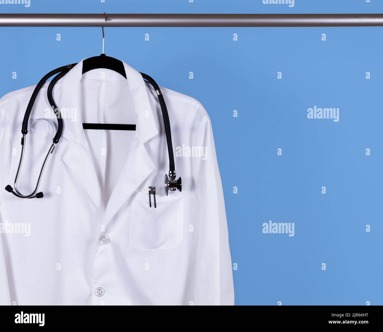 White scrub shirt for medical professional hanging on blue wall Stock Photo