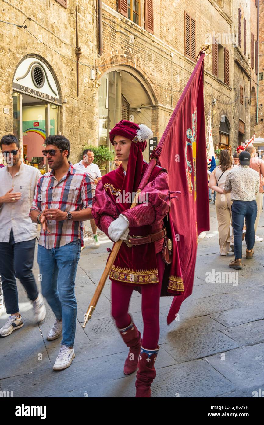 Man dressed in medieval costume and carrying flag of one of the Contrada on Via di Città in Siena, Tuscany, Italy Stock Photo