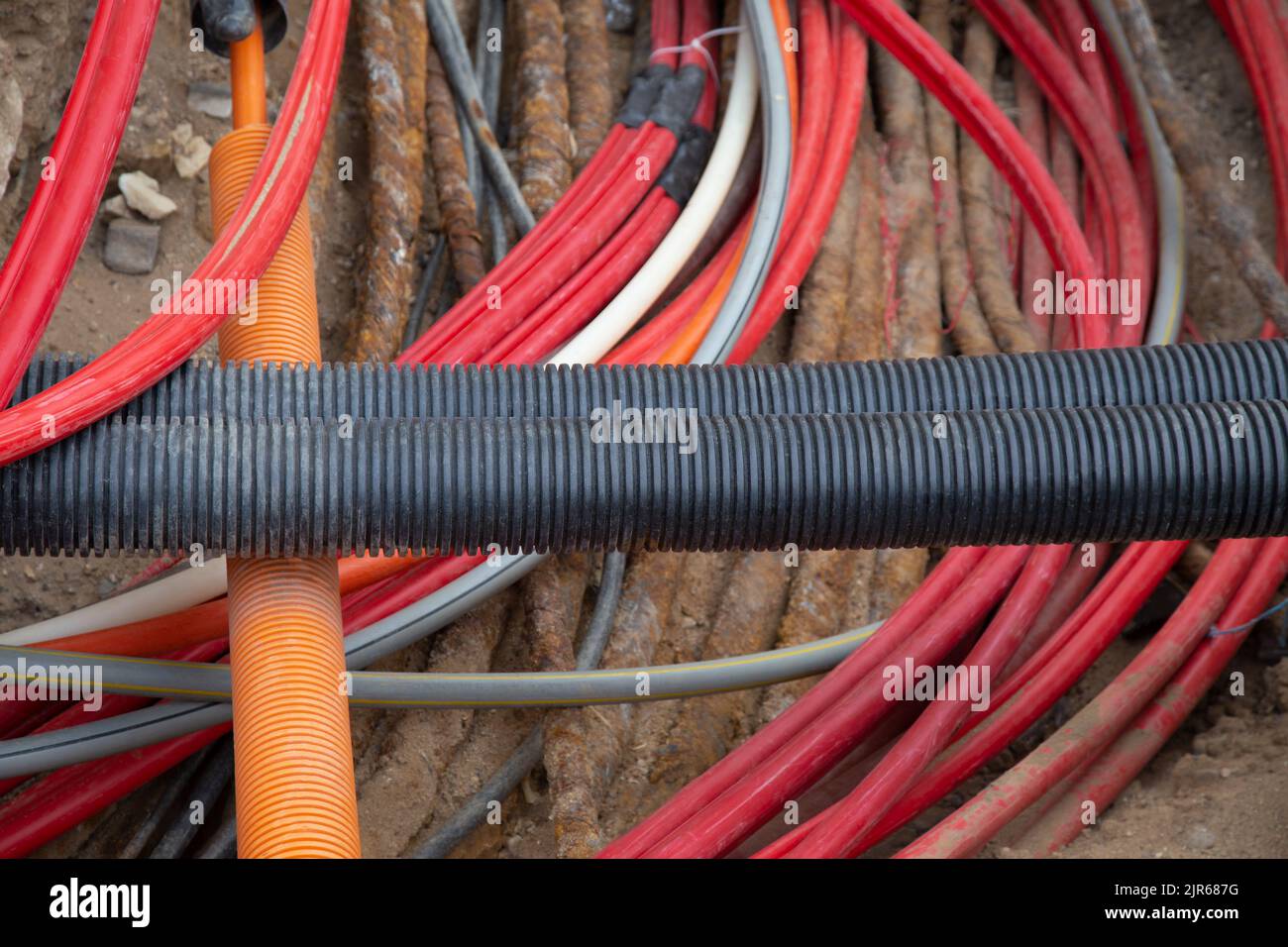 Network cables in red corrugated pipe are buried underground on the