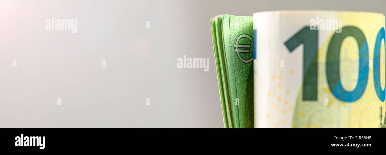 Roll of money. Roll of 100 euro banknotes. Euro banknotes rolled up on a gray background. The concept of financial assistance, real estate purchase Stock Photo