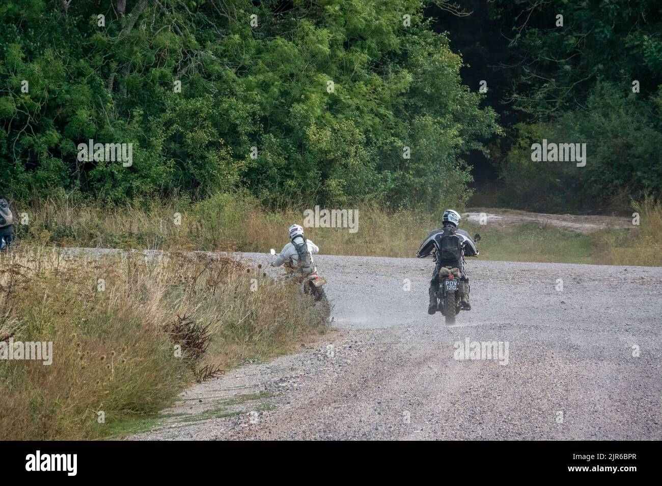 two motor cyclists (bikers) riding their off-road motorbikes along a ...