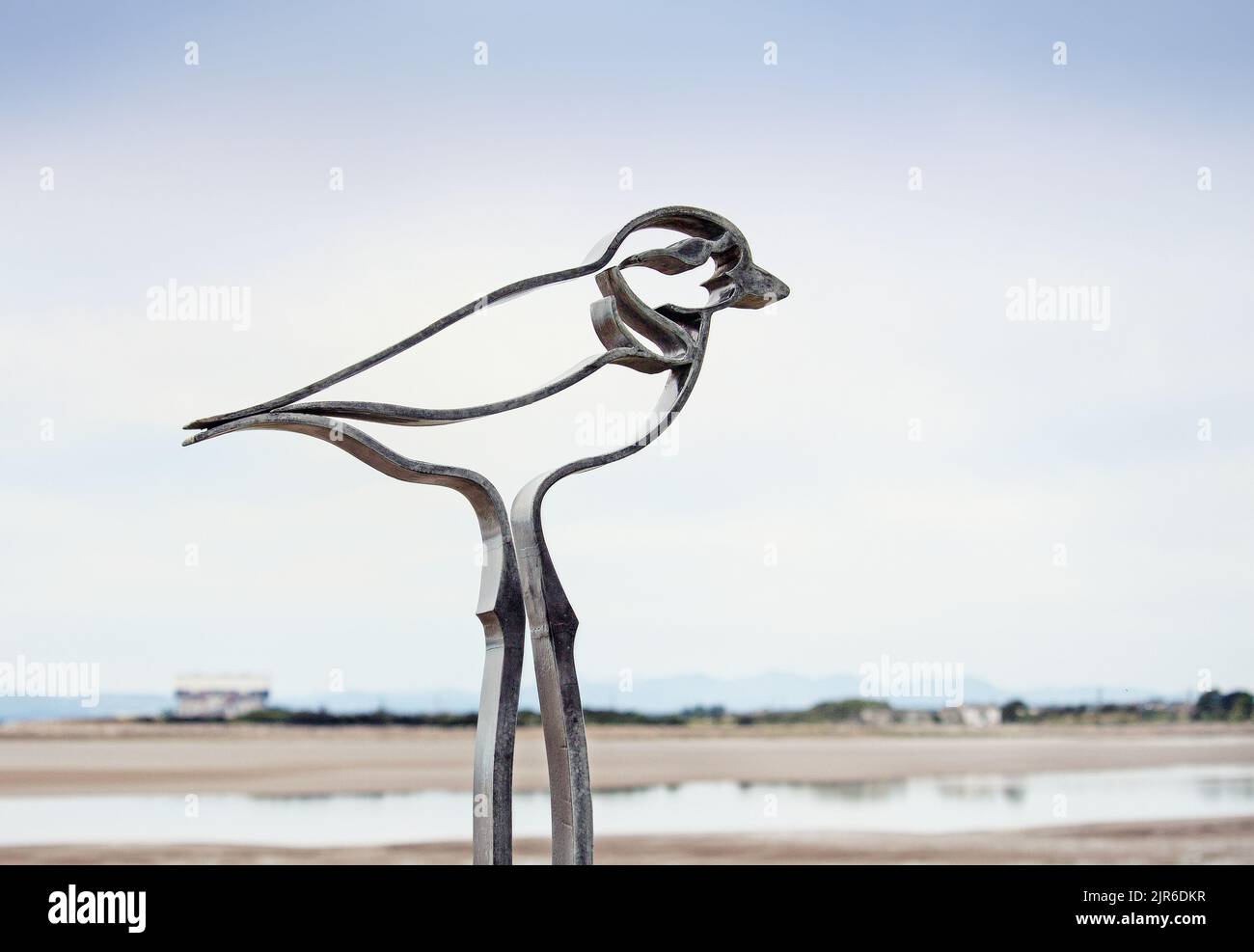 The concept of a distant shore, with a manufactured metallic bird in the foreground Stock Photo