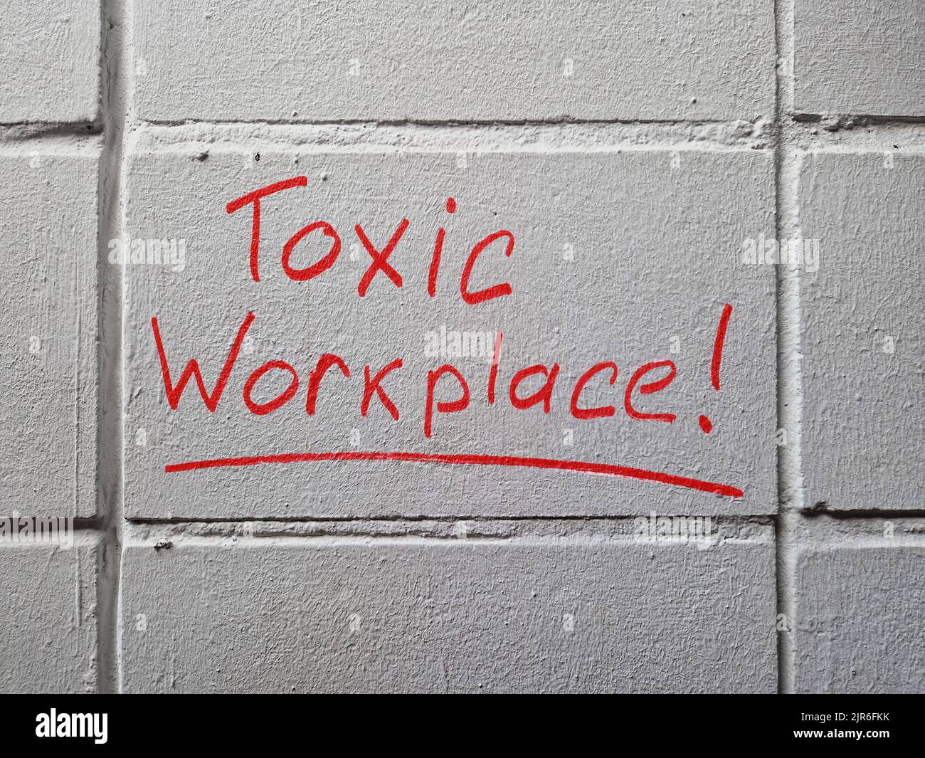 Toxic workplace words handwritten on the wall. Stock Photo