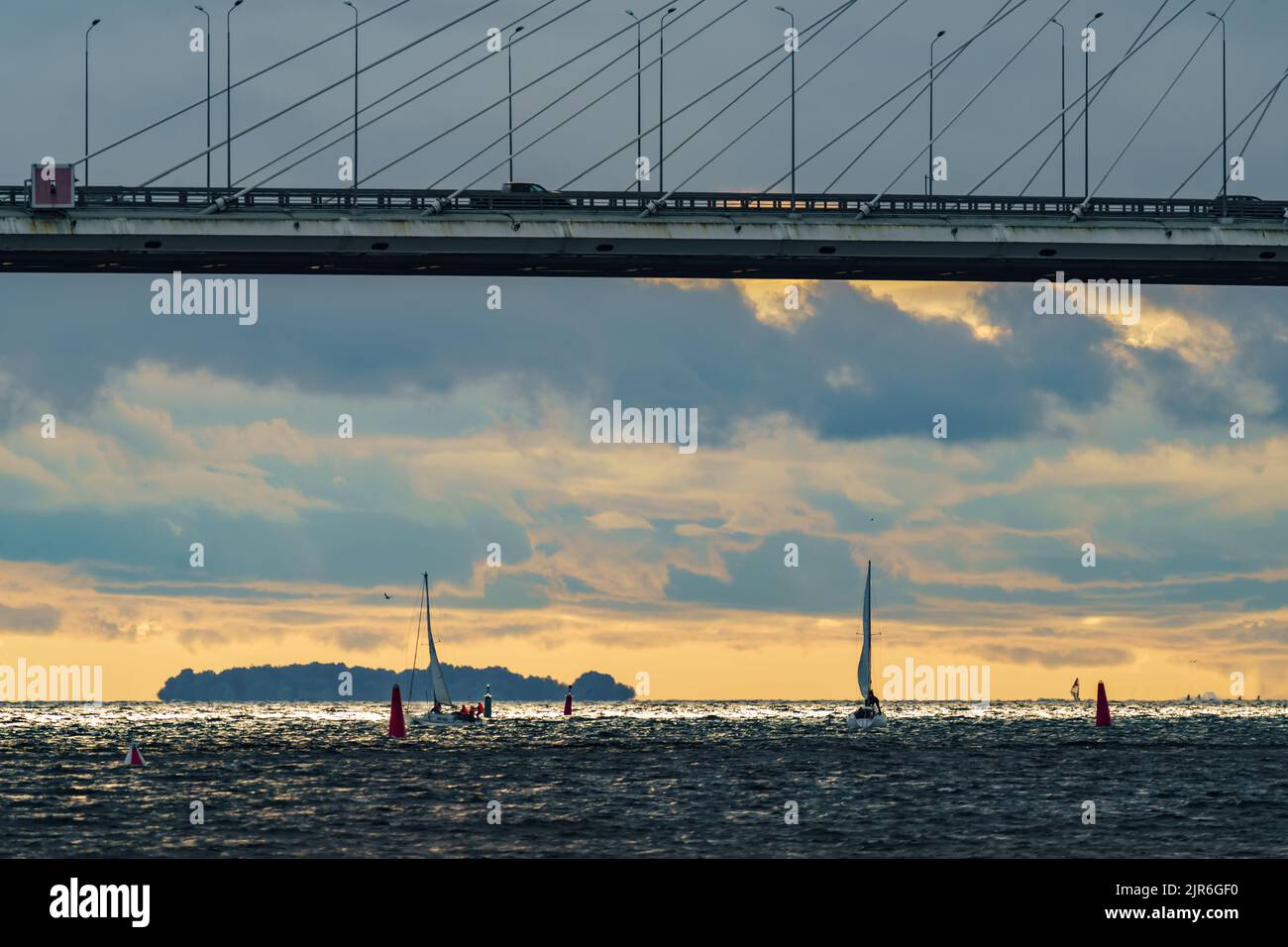 Russia, St. Petersburg, 29 July 2022: Few small sport sailing boats at sunset with stormy sky, highly cable-stayed bridge on background Stock Photo