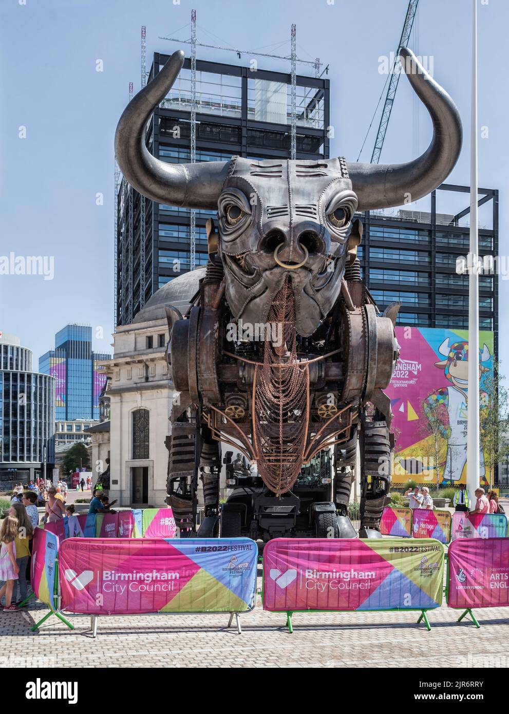People look in wonder at the iconic 10 metre high raging bull from the 2022 Commonwealth Games opening ceremony. Centenary Square, Birmingham, England. Stock Photo
