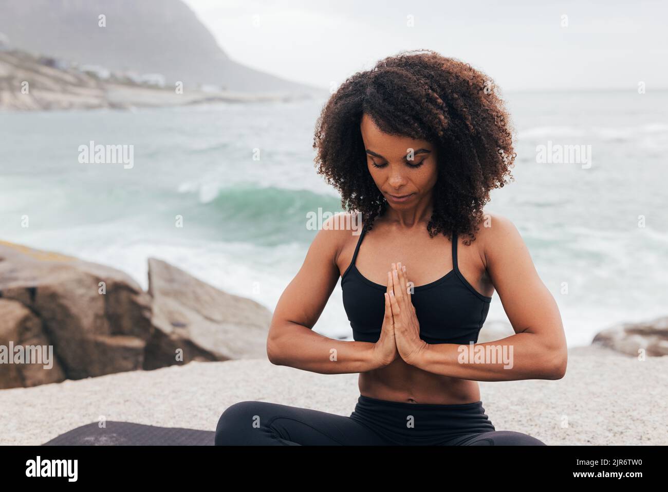 Woman with closed eyes sitting in prayer pose. Female practicing yoga with folded hands. Stock Photo