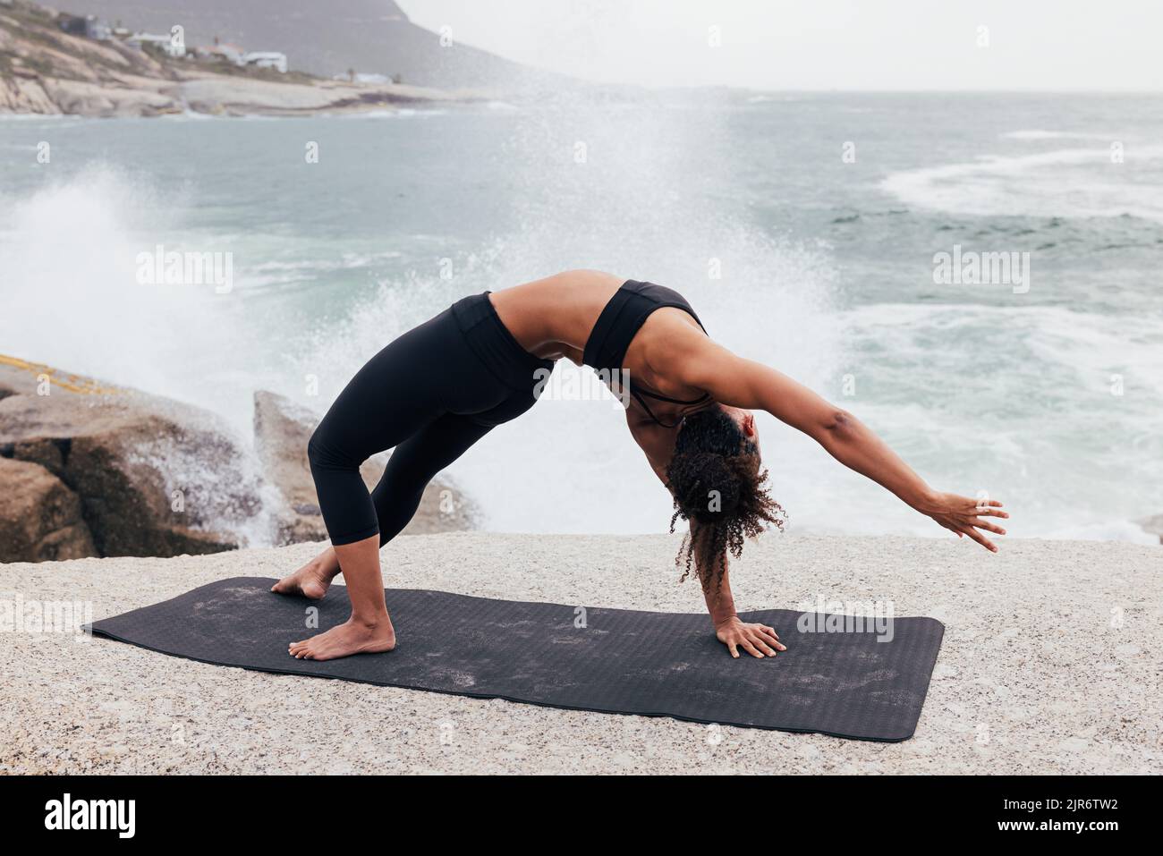 Woman practicing side plank pose by ocean. Young woman doing yoga exercise outdoors. Stock Photo