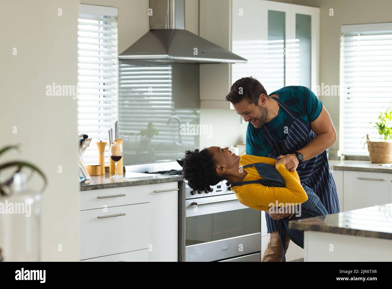 Image of happy diverse couple dancing in kitchen Stock Photo